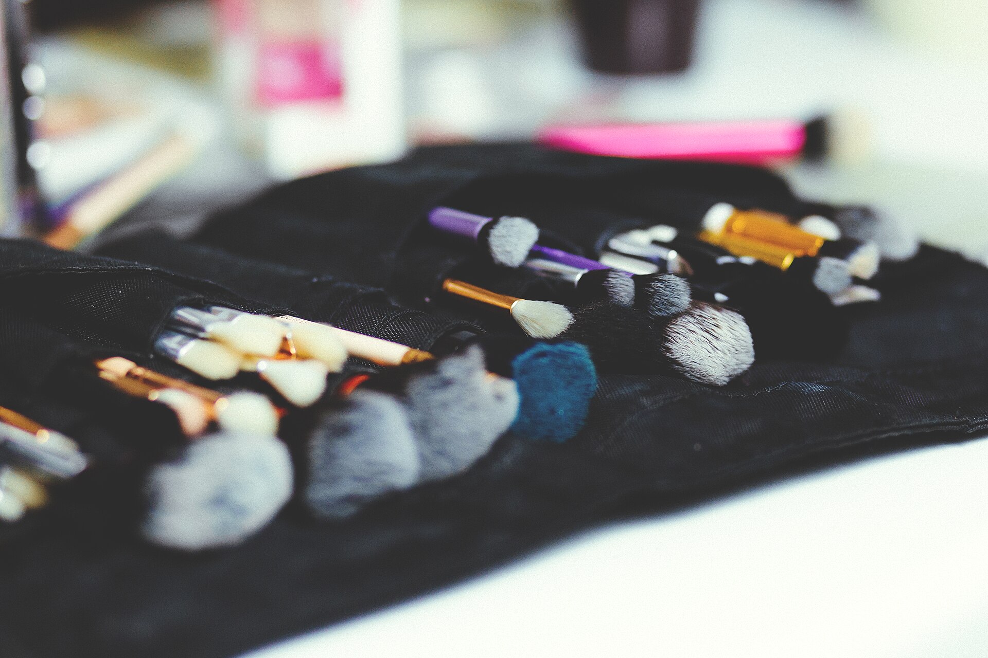 A bundle of makeup and styling brushes in assorted sizes resting on black fabric